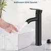A hand is filling a glass with water from a black bathroom sink faucet. An inset diagram shows the faucet's water flow. Produktbild-Vorschau
