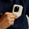 A hand is placing a phone with a wallet case into a navy jacket pocket. Náhled obrázku produktu
