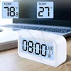 A white digital alarm clock is shown on a wooden desk, with a laptop in the background. Insets show temperature readings in Fahrenheit and Celsius. Voir les images du produit