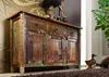A rustic wooden sideboard with multiple drawers and cabinets, decorated with various items on top and flanking duck figurines.