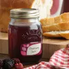 A jar of blackberry jam is placed on a wooden board next to sliced bread and a red and white checkered cloth. Voir les images du produit