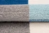 A close-up view of a rolled-up rug with distinct color blocks. Náhled obrázku produktu