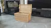 A wicker chest with its lid open is placed on a tiled floor in front of a modern entertainment center and fireplace. Voir les images du produit