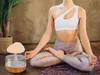 A person is meditating next to a mushroom-shaped humidifier. Náhled obrázku produktu