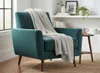A teal armchair with a gray throw blanket draped over it, placed in a well-lit room with a bookshelf and a side table. Náhľad obrázku produktu