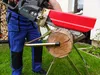 A person is using a chainsaw on a log holder outdoors. Náhled obrázku produktu
