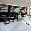 A woman is vacuuming a retail store with a Nilfisk vacuum cleaner. Produktbild-Vorschau
