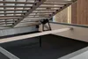 Close-up view of the underside of a bed frame, showing the wooden slats, support beams, and lifting mechanism for a storage compartment. Náhled obrázku produktu