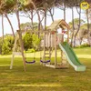 A wooden playground set with a slide and swings in a grassy outdoor area with trees. Produktbild-Vorschau