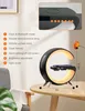 A bedside lamp with a wireless charger and Bluetooth speaker, shown on a table with a diagram explaining its features. Produktbild-Vorschau
