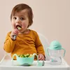 A baby eating pasta in a high chair with a B.BOX bottle and bowl. Produktbild-Vorschau