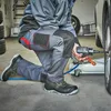 A person is working on a car tire in a garage. Produktbild-Vorschau