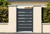 A modern gray aluminum gate and matching garden gate are shown in front of a house, flanked by beige pillars and lush green bushes. Produktbild-Vorschau
