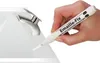 A hand is using a white marker pen labeled 'Emaille-Fix' to touch up a white sink or bathtub near a chrome faucet. Produktbild-Vorschau
