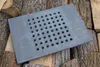 A cast iron grate with holes is placed on a pile of firewood. Náhled obrázku produktu