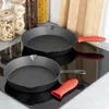 Two cast iron frying pans are displayed on a black induction stovetop, with kitchen items like jars of pasta and cereal in the background. Anteprima dell’immagine prodotto
