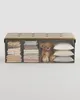 A storage bench with tufted lid, filled with folded linens, a teddy bear, and pillows. Náhled obrázku produktu