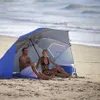 A couple relaxing under a beach umbrella on a sandy beach. Anteprima dell’immagine prodotto
