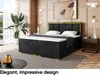 A bedroom scene featuring a large boxspring bed with a headboard, mattress, and topper. The room has decorative wall paneling, a large plant, and a side table with decorative items. Produktbild-Vorschau