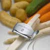 A close-up shot of a vegetable peeler with a logo on it, surrounded by various vegetables like potatoes, carrots, and asparagus. Anteprima dell’immagine prodotto