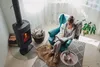 A woman reading a book in a cozy armchair next to a fireplace. Náhled obrázku produktu