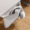 A close-up of a gray fabric pocket on a chair with white headphones inside. Voir les images du produit