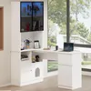 A white corner desk with a built-in cabinet and shelving unit, placed in a room with a large window overlooking a modern house and trees. Anteprima dell’immagine prodotto