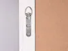 Close-up of the back of a white wooden frame, showing a metal hanging bracket with screws and a piece of brown backing material. Produktbild-Vorschau