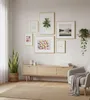 A living room scene with a gallery wall of framed pictures above a wooden media console. Produktbild-Vorschau
