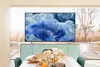 A modern living room with a large TV displaying a colorful abstract image, set against a backdrop of a large window overlooking a winter landscape. A dining table with food and flowers is in the foreground. Anteprima dell’immagine prodotto