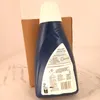 A bottle of cleaning solution is shown leaning against a cardboard box. Voir les images du produit