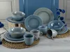 A collection of blue and gray ceramic dishes and mugs arranged on a table. Produktbild-Vorschau