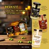 A marketing image showcasing a beer gift box with three jars of mustard, set against a blurred background of a pub or brewery. Produktbild-Vorschau