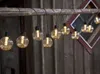 A string of LED lights hanging from a wooden beam, with a wooden wall in the background. Podgląd zdjęcia produktu