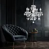 A luxurious dark room with a tufted armchair, a small side table with decorative items, and a crystal chandelier. Anteprima dell’immagine prodotto