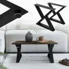 A coffee table with black X-shaped legs, a vase, and a mug on top, placed in a living room setting. Podgląd zdjęcia produktu