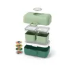 An exploded view of a green lunchbox with multiple compartments and accessories. Produktbild-Vorschau