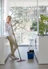 A woman is cleaning a modern kitchen with a mop. Produktbild-Vorschau