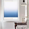 A close-up view of a window with gradient blue and white blinds, in a room with a radiator and a table with chairs. Produktbild-Vorschau