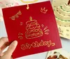 A hand holding a red birthday card with gold foil decorations. Podgląd zdjęcia produktu