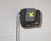A battery charger is mounted on a white brick wall. Produktbild-Vorschau