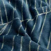 A close-up view of a textured blue fabric with gold stripes. Podgląd zdjęcia produktu