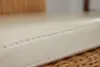 A close-up of a beige seat cushion with visible stitching. Produktbild-Vorschau