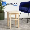 A wooden stool is placed on a grey carpet next to a potted plant and a blue chair. The KADAX HOME logo is visible in the background. Voir les images du produit