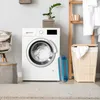 A laundry room scene with a washing machine, laundry basket, and a folding laundry basket. Náhľad obrázku produktu