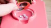 A hand is placing a sticker of a cartoon character onto a pink crafting machine. Anteprima dell’immagine prodotto