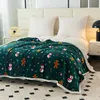 A dark green blanket with a Christmas-themed pattern of snowmen and gingerbread men is spread across a bed with white pillows. Produktbild-Vorschau