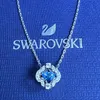 A Swarovski necklace with a blue crystal pendant is displayed on a blue box with the Swarovski logo and name. Produktbild-Vorschau