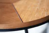 A close-up shot of a round wooden table with a black metal frame. Produktbild-Vorschau