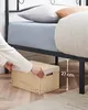 A person is placing a storage basket under a bed frame. Podgląd zdjęcia produktu